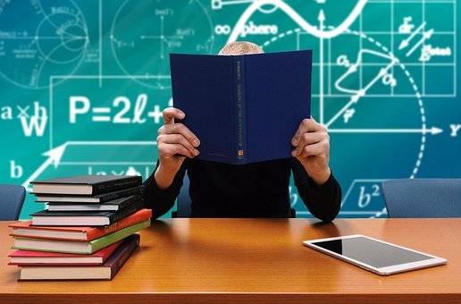 Pizarrón con formulas, persona tapada con libro